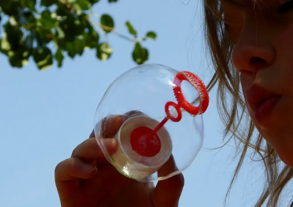 Faire des bulles de savon, un des jeux de plein air à jouer seul appréciés des tout-petits.