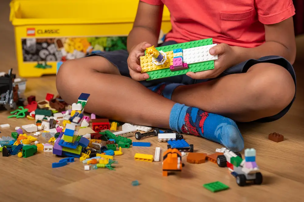 Enfant jouant avec une boîte de briques Lego