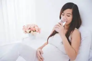 Femme enceinte en train de boire un verre d'eau