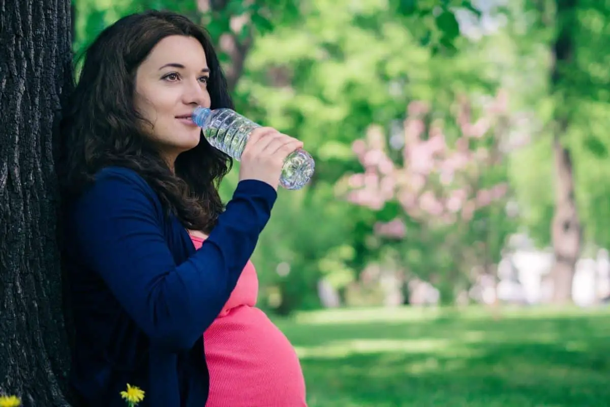 Femme buvant de l'eau minérale enceinte