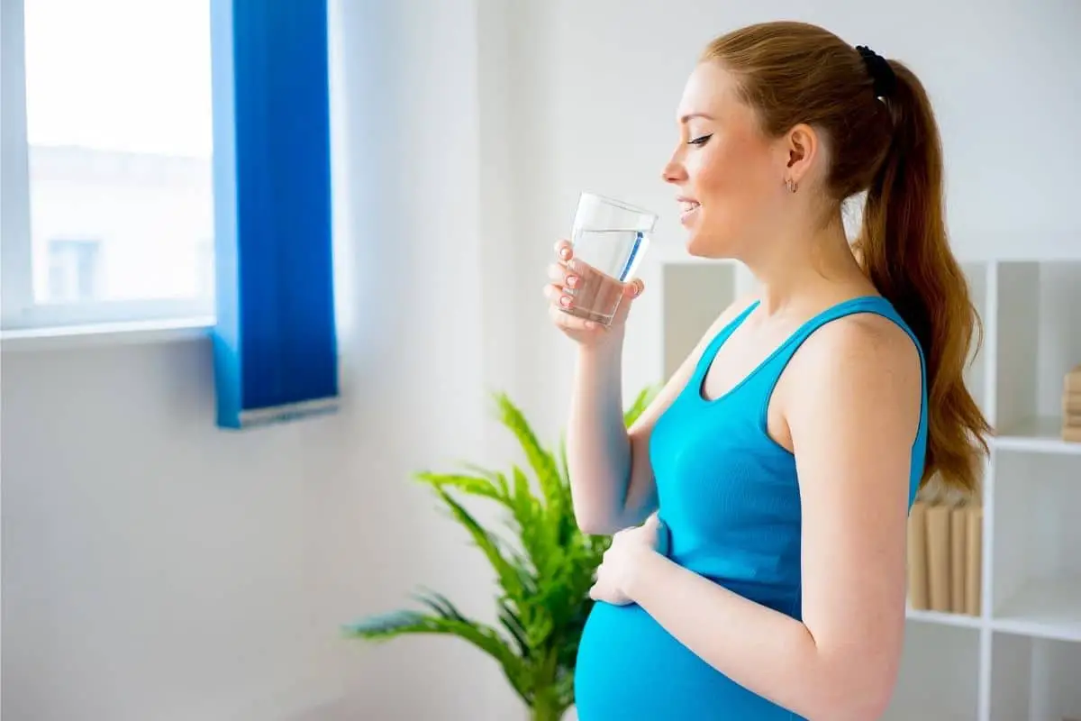 Femme enceinte buvant de l'eau du robinet