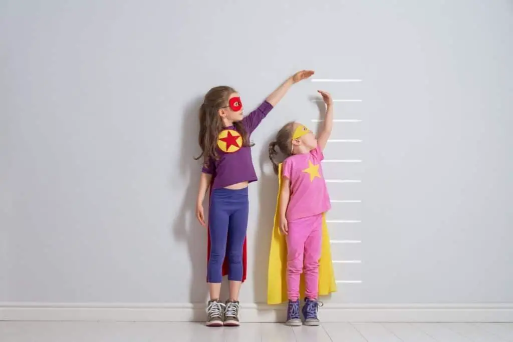 Petites filles en train de comparer leur taille sur une toise