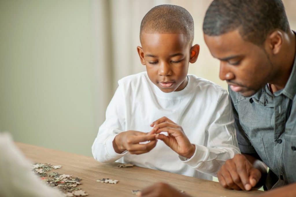 Jeune garçon en train de faire un puzzle avec son père