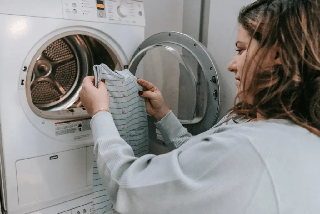 Maman en train de mettre une gigoteuse dans le lave-linge